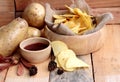 Potato chip and fresh potatoes on wood background Royalty Free Stock Photo