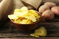 Potato chips in bowl on brown wooden background. Royalty Free Stock Photo