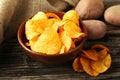 Potato chips in bowl on brown wooden background. Royalty Free Stock Photo