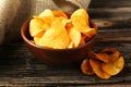 Potato chips in bowl on brown wooden background. Royalty Free Stock Photo