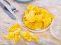 Potato chips in bowl on background. Salty crisps scattered on table Royalty Free Stock Photo