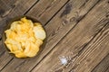 Potato chips in bowl on a wooden background, top view. Salty crisps scattered on a table Royalty Free Stock Photo