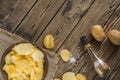Potato chips in bowl on a wooden background, top view. Salty crisps scattered on a table Royalty Free Stock Photo