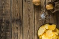 Potato chips in bowl on a wooden background, top view. Salty crisps scattered on a table Royalty Free Stock Photo