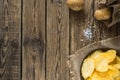 Potato chips in bowl on a wooden background, top view. Salty crisps scattered on a table Royalty Free Stock Photo