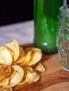Potato chips, classic beer glass and green bottle with lager beer on a wooden board. Dark background. Crisps and ale. Food and Royalty Free Stock Photo