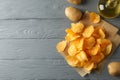 Potato chips on craft paper, sault, oliv oil, potato on gray wooden background, space for text