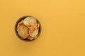 Potato chips, crisp unhealthy chips, junk food, fast food concept. Potato chips in a bowl over bright yellow background.