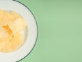 Potato chips or crisps in a white dish on a green background Royalty Free Stock Photo