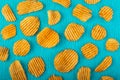 Potato chips, grooved gold chips, corrugated crispy snacks on a turquoise background, colored pattern. Unhealthy fast food. Salted