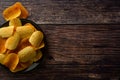 Potato chips over wooden background. Salty crispy snack. Copy space