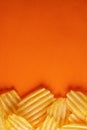 Potato chips, ribbed and fluted, shot from above on a bright orange background. vertical layout and concept, copyspace Royalty Free Stock Photo