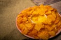 Potato chips on a round platter and a saucepan with cheese sauce. Close up Royalty Free Stock Photo