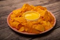 Potato chips on a round platter and a saucepan with cheese sauce. Close up Royalty Free Stock Photo