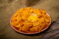 Potato chips on a round platter and a saucepan with cheese sauce. Close up Royalty Free Stock Photo
