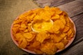 Potato chips on a round platter and a saucepan with cheese sauce. Close up Royalty Free Stock Photo