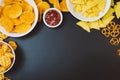 Potato chips and snacks on black slate table, top view Royalty Free Stock Photo