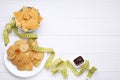 Potato chips, tomato sauce and measuring tape on white wooden table, flat lay with space for text. Weight loss concept