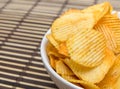 Potato chips in white bowl on bamboo mat