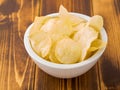 Potato chips in white bowl on brown wooden table Royalty Free Stock Photo