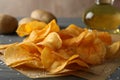 Potato crispy chips on craft paper, sault, oliv oil, potato on gray wooden background, space for text