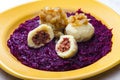 Potato dumplings filled with smoked meat with fried onion on red cabbage Royalty Free Stock Photo