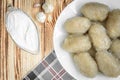 Potato dumplings with stuffed minced meat on a white plate and gravy boat with sour cream on wooden background Royalty Free Stock Photo