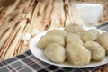 Potato dumplings with stuffed minced meat on a white plate and gravy boat with sour cream on wooden background Royalty Free Stock Photo
