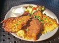 Potato fritters served with sour cream, herbs and salad of fresh seasonal vegetables closeup.