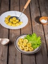 Potato gnocchi on two plates, leaves of fresh leaf lettuce on light plates on an old plank table. Near a wooden spoon with coarse Royalty Free Stock Photo