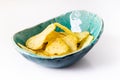 Potato grooved chips in a homemade ceramic plate turquoise on a white background