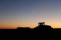 A silhouette of a tractor harvesting potatoes at night