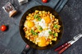 Potato hash with eggs and herbs for breakfast on black stone background Royalty Free Stock Photo