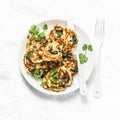 Potato latkes with spinach and herbs on a light background, top view. Delicious breakfast