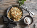 Potato, leek and green pea pancakes in the pan on wooden background, top view