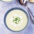 Potato leek soup in blue ceramic bowl garnished with french cream and green onion, served with croutons, top view, square format Royalty Free Stock Photo