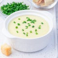 Potato leek soup in white ceramic bowl garnished with green onion served with croutons, square format, closeup Royalty Free Stock Photo