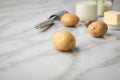 Potato, milk, salt, butter, nutmeg as ingredients with press and grinder for mashed potatoes on light marble background