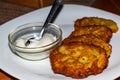 Potato pancakes or draniki with sour cream in a plate on a wooden table.