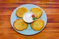 Potato pancakes or latkes on a blue plate of rustic wooden surface with sour cream Royalty Free Stock Photo