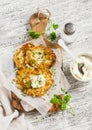 Potato pancakes or latkes with cream served on olive cutting Board over white wooden table. Rustic style.