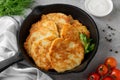 Potato pancakes, latkes or draniki with fresh herbs and sour cream in a cast iron pan on a gray concrete background. Top view, Royalty Free Stock Photo