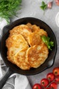 Potato pancakes, latkes or draniki with fresh herbs and sour cream in a cast iron pan on a gray concrete background. Top view, Royalty Free Stock Photo