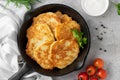 Potato pancakes, latkes or draniki with fresh herbs and sour cream in a cast iron pan on a gray concrete background. Top view Royalty Free Stock Photo