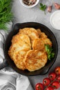 Potato pancakes, latkes or draniki with fresh herbs and sour cream in a cast iron pan on a gray concrete background. Top view, Royalty Free Stock Photo