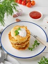 Potato pancakes, latkes or draniki with fresh herbs and sour cream on a plate on a white wooden background. Top view, copy space Royalty Free Stock Photo