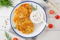 Potato pancakes, latkes or draniki with fresh herbs and sour cream on a plate on a white wooden background. Top view, copy space Royalty Free Stock Photo