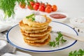 Potato pancakes, latkes or draniki with fresh herbs and sour cream on a plate on a white wooden background. Top view, copy space