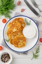 Potato pancakes, latkes or draniki with fresh herbs and sour cream on a plate on a white wooden background. Top view, copy space Royalty Free Stock Photo