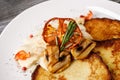 Potato pancakes with mushrooms and tomato on a white plate